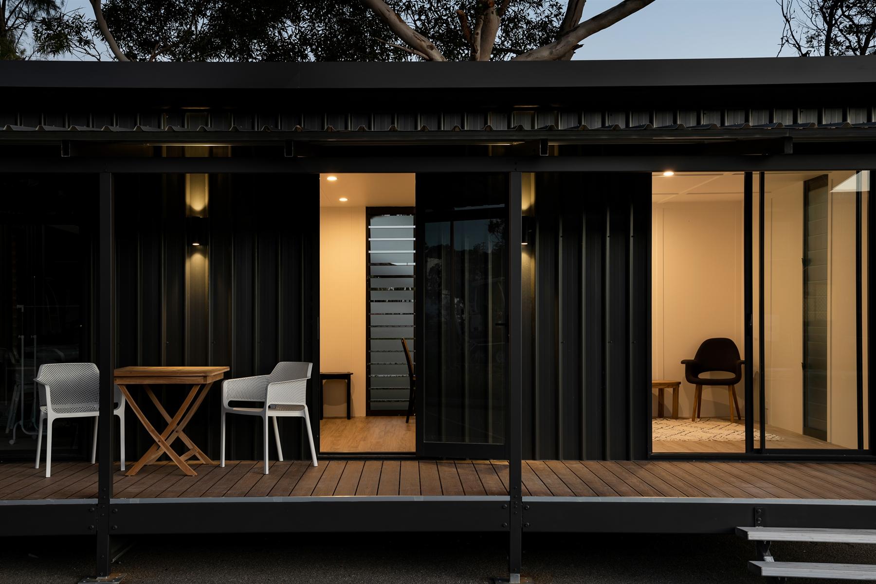 Black-framed swing and sliding doors lit at dusk