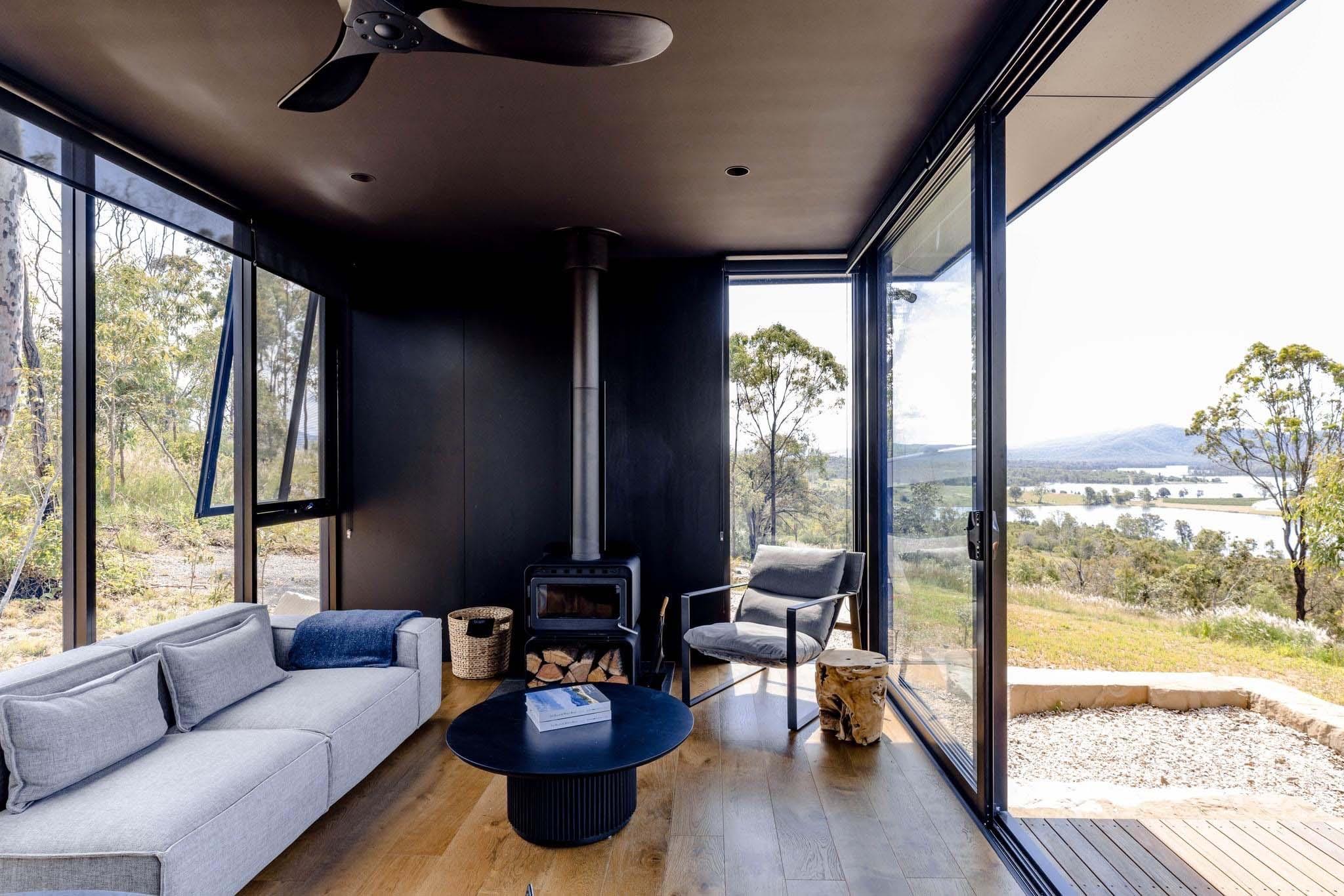 Living room with black-framed awning windows, fixed glass and sliding doors overlooking a valley